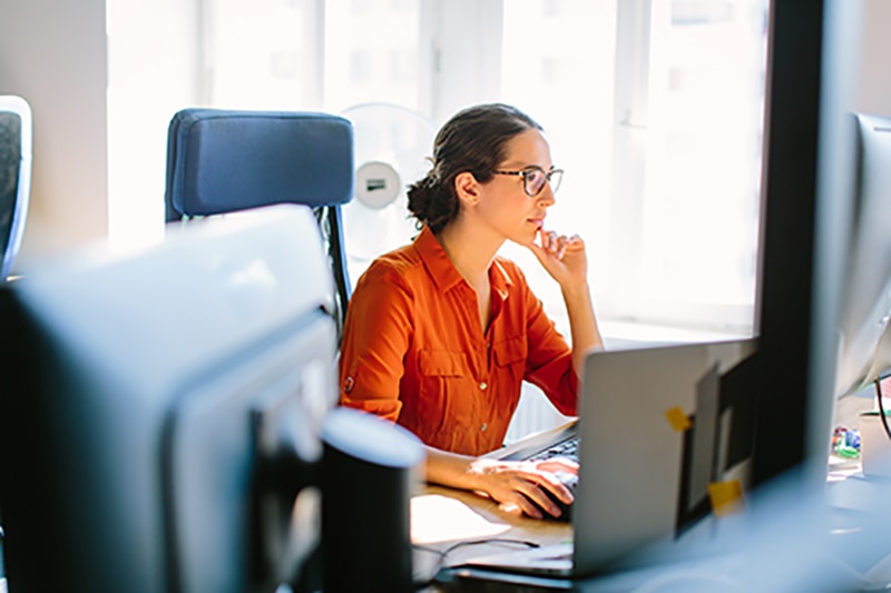 Business woman sitting at her desk and working on desktop computer